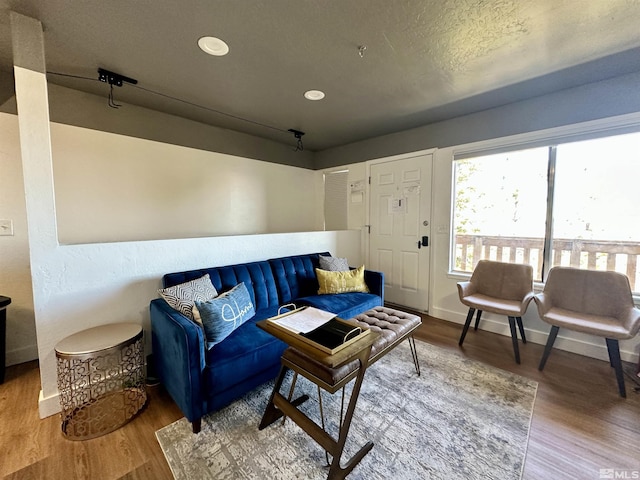 living area with recessed lighting, a textured ceiling, baseboards, and wood finished floors