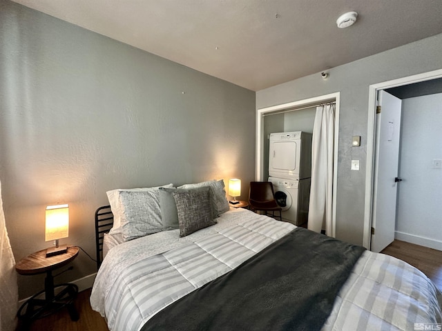 bedroom with stacked washing maching and dryer, baseboards, and dark wood-style flooring