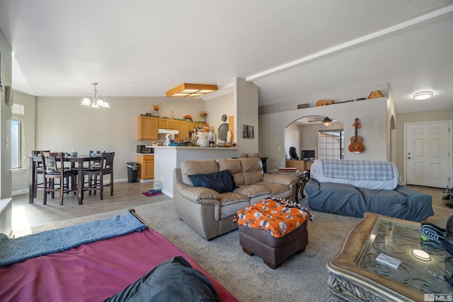 living room with ceiling fan with notable chandelier, vaulted ceiling, and light wood-type flooring