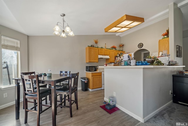 dining space with vaulted ceiling, a notable chandelier, and light hardwood / wood-style flooring