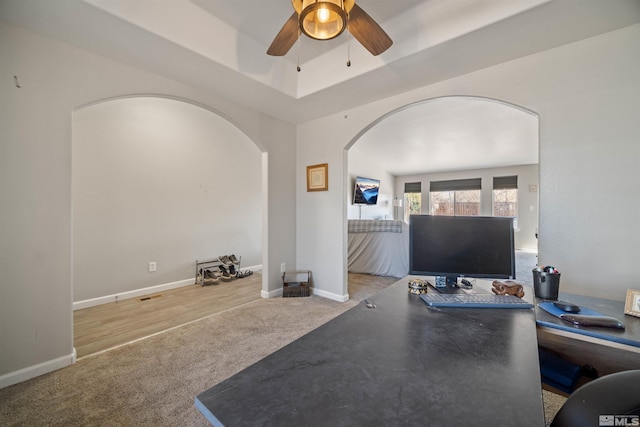 living room with light carpet, a tray ceiling, and ceiling fan