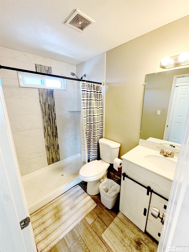 bathroom with wood-type flooring, toilet, vanity, and a shower with shower curtain