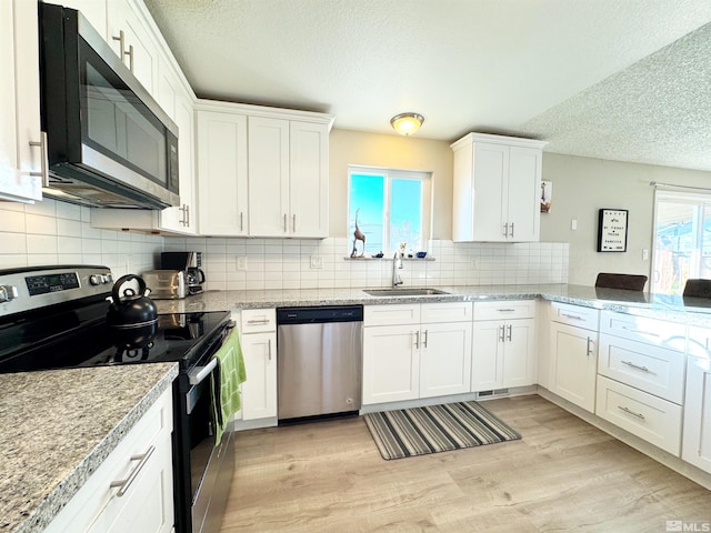 kitchen with stainless steel appliances, sink, white cabinets, and light hardwood / wood-style floors