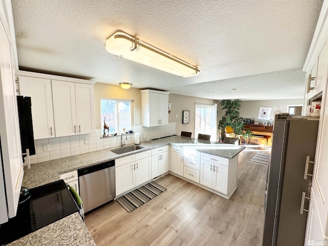 kitchen with stainless steel appliances, kitchen peninsula, sink, and white cabinets