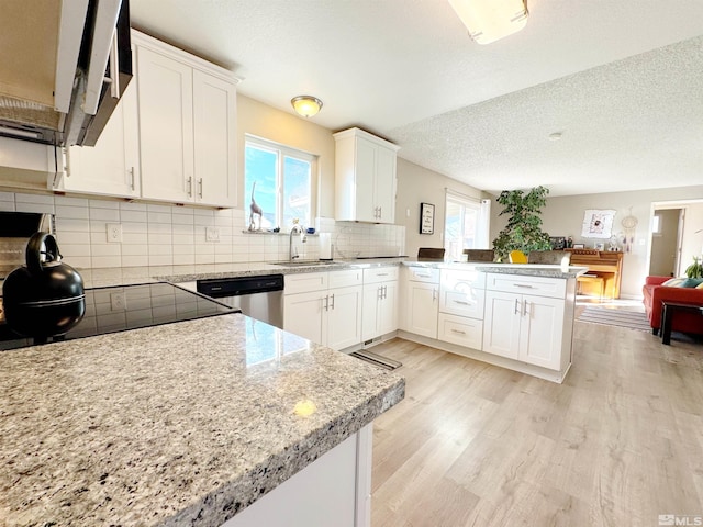 kitchen with white cabinetry, sink, light hardwood / wood-style floors, kitchen peninsula, and stainless steel appliances