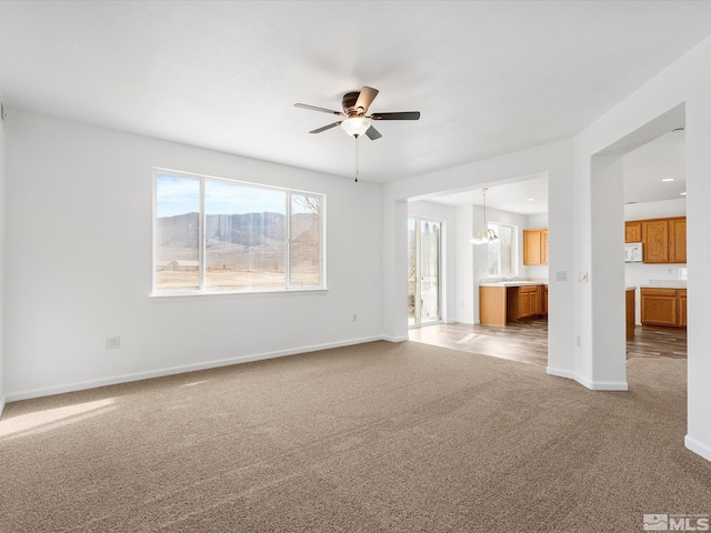 unfurnished living room featuring ceiling fan and carpet floors