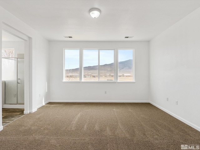 spare room featuring a mountain view and dark carpet