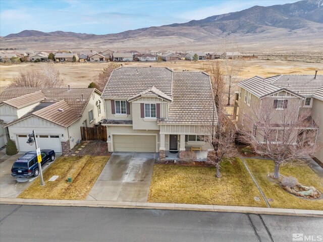 exterior space with a garage, a mountain view, and a front lawn