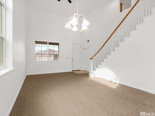 unfurnished living room with a high ceiling, carpet floors, and a notable chandelier