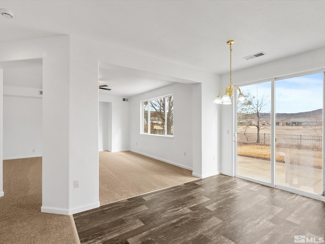 empty room with wood-type flooring, a mountain view, and an inviting chandelier