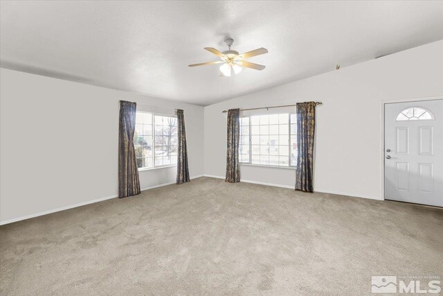 interior space with ceiling fan, lofted ceiling, light carpet, and a textured ceiling