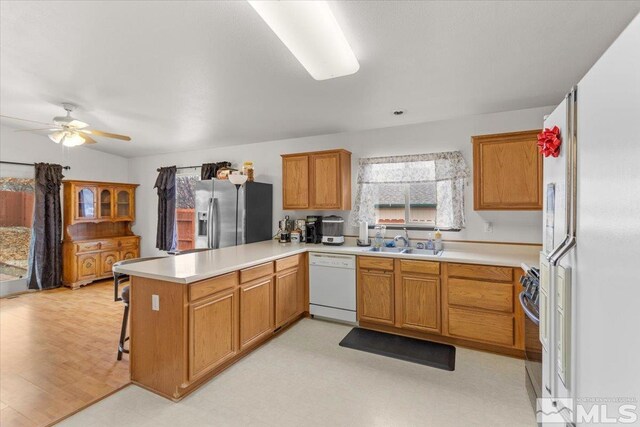 kitchen with stainless steel refrigerator with ice dispenser, sink, range, white dishwasher, and kitchen peninsula