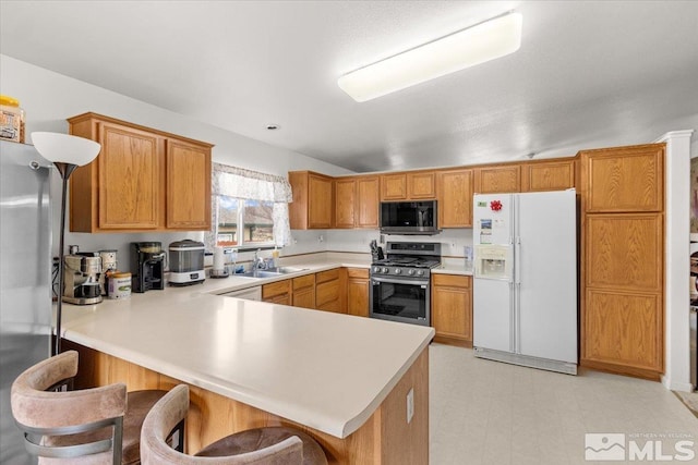 kitchen with stainless steel appliances, sink, a breakfast bar area, and kitchen peninsula