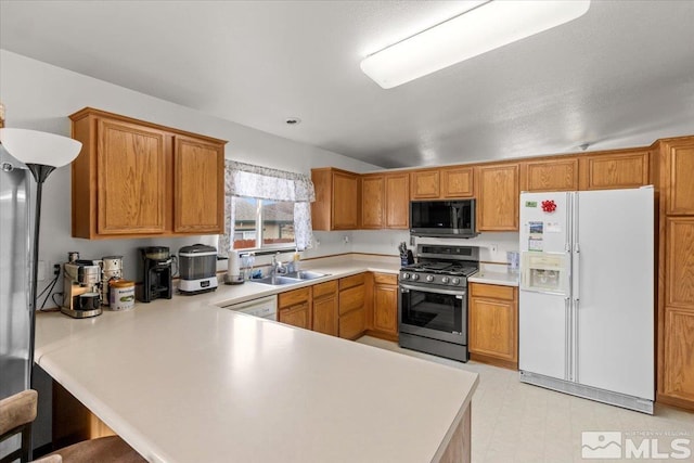 kitchen featuring a kitchen bar, sink, white appliances, and kitchen peninsula