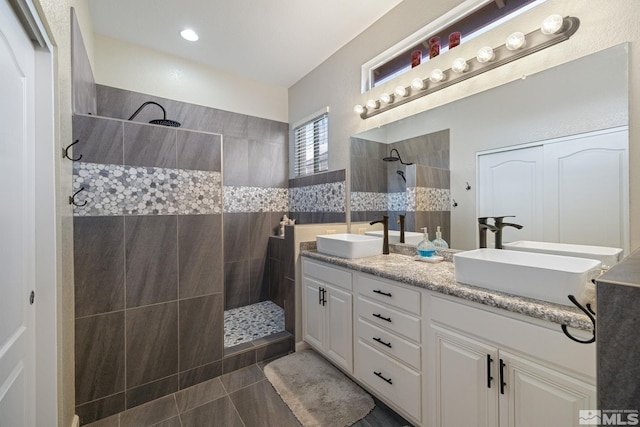 bathroom featuring tile patterned flooring, vanity, and a tile shower