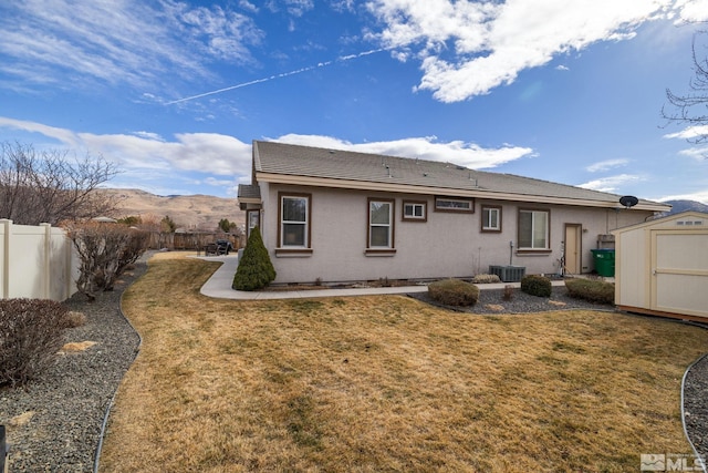 back of property with a storage shed, a patio area, central AC unit, a lawn, and a mountain view