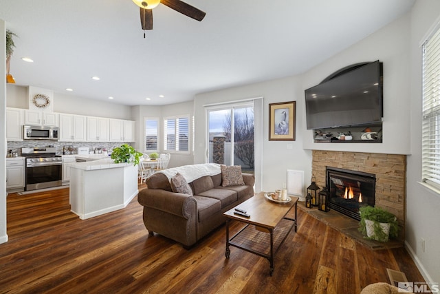 living room with dark wood-type flooring, ceiling fan, and a fireplace