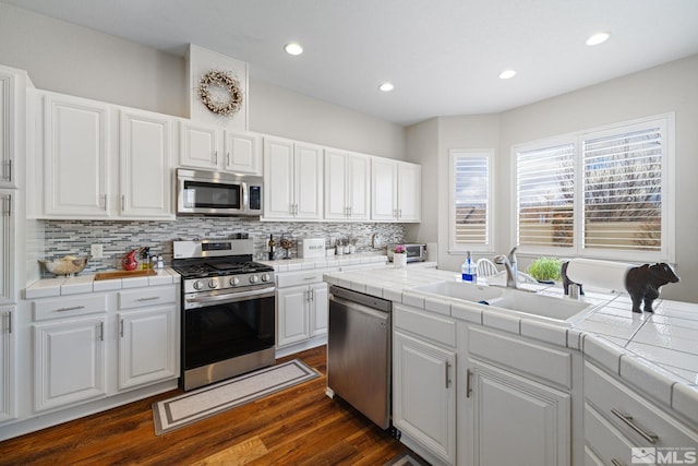 kitchen featuring appliances with stainless steel finishes, tile countertops, sink, and white cabinets