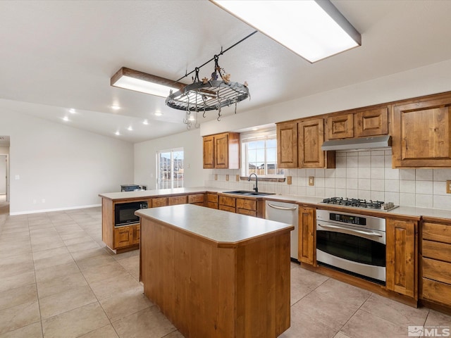 kitchen with vaulted ceiling, appliances with stainless steel finishes, sink, decorative backsplash, and a center island