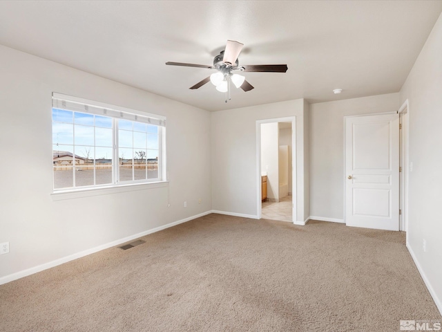 unfurnished bedroom with ceiling fan, light colored carpet, and ensuite bathroom