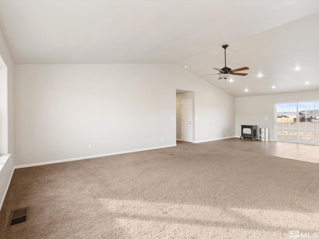 unfurnished living room with lofted ceiling, a wood stove, ceiling fan, and carpet flooring