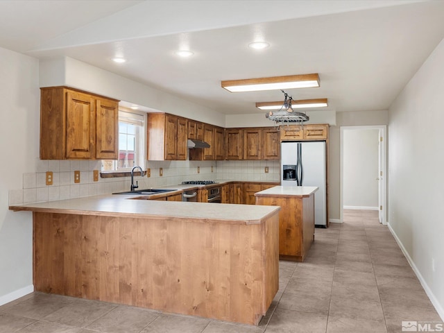 kitchen featuring stainless steel refrigerator with ice dispenser, sink, backsplash, and kitchen peninsula