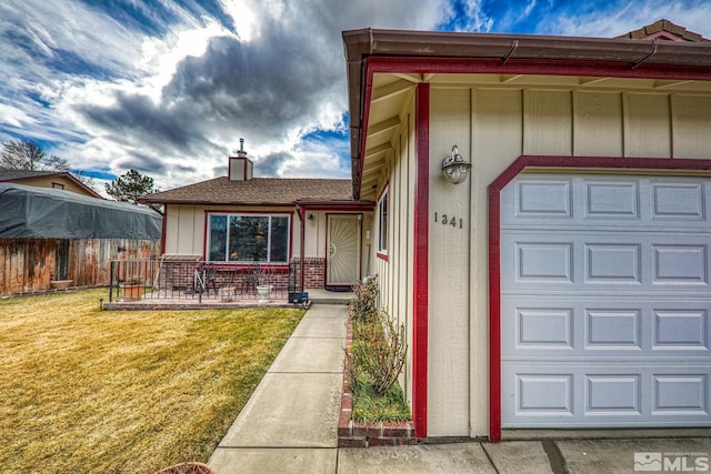 view of exterior entry featuring a garage and a yard