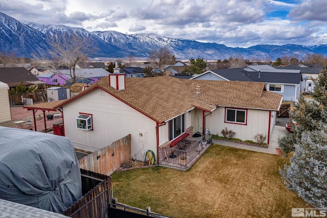 back of property featuring a mountain view and a lawn