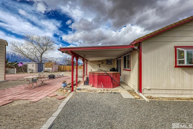 view of yard featuring a storage unit, a hot tub, a mountain view, and a patio