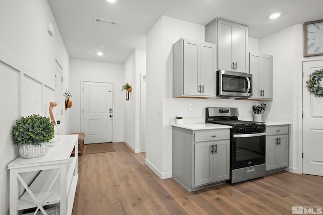 kitchen with stainless steel appliances, dark wood-type flooring, and gray cabinetry