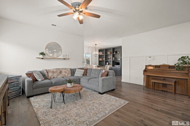 living room with dark hardwood / wood-style flooring and ceiling fan with notable chandelier