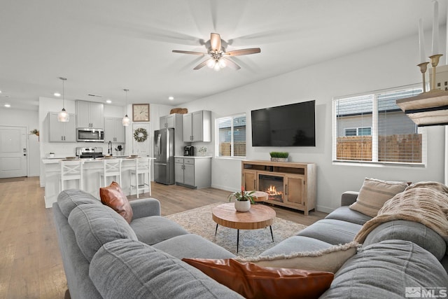 living room featuring sink, ceiling fan, and light hardwood / wood-style flooring