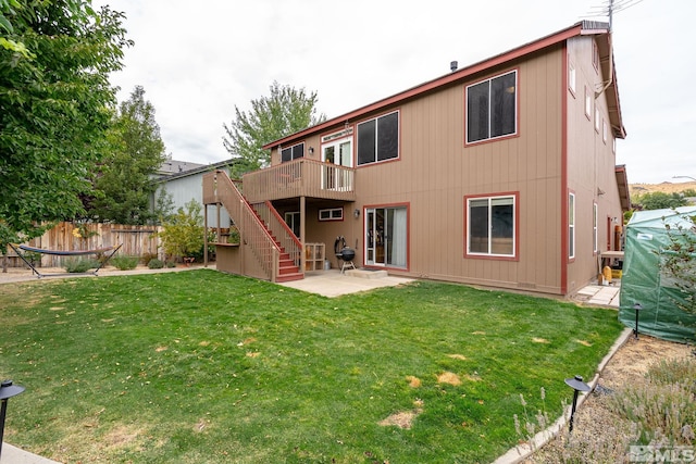 rear view of property featuring a deck, a patio area, and a lawn