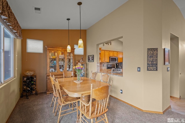 dining room featuring high vaulted ceiling and light colored carpet