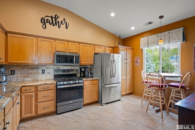 kitchen with lofted ceiling, pendant lighting, stainless steel appliances, light stone countertops, and backsplash