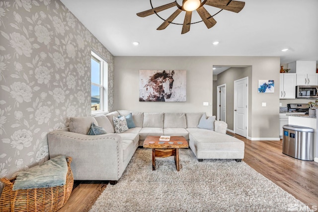 living room with ceiling fan and light wood-type flooring