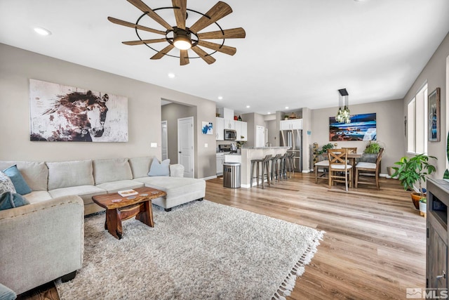 living room with ceiling fan and light wood-type flooring