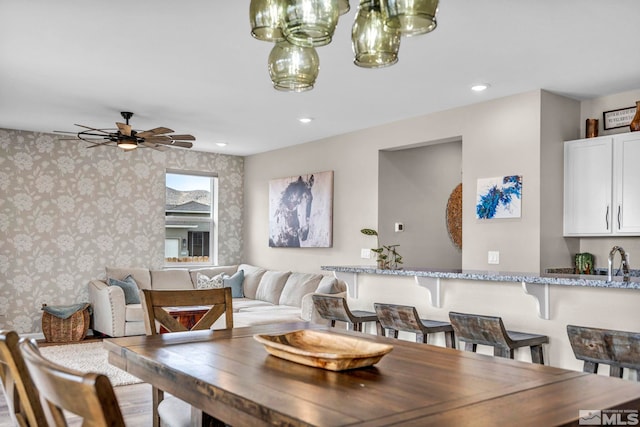 dining space with hardwood / wood-style flooring, ceiling fan, and sink