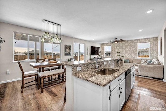 kitchen featuring pendant lighting, sink, white cabinetry, an island with sink, and a kitchen bar