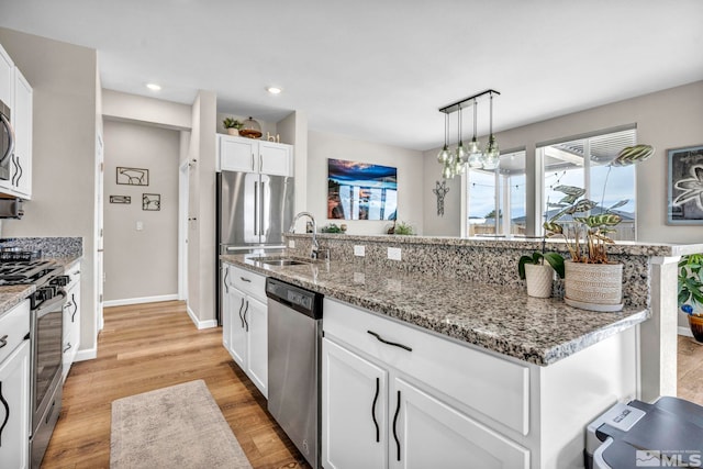 kitchen with white cabinetry, sink, hanging light fixtures, a kitchen island with sink, and stainless steel appliances