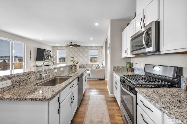 kitchen featuring stone counters, hardwood / wood-style floors, sink, white cabinets, and stainless steel appliances