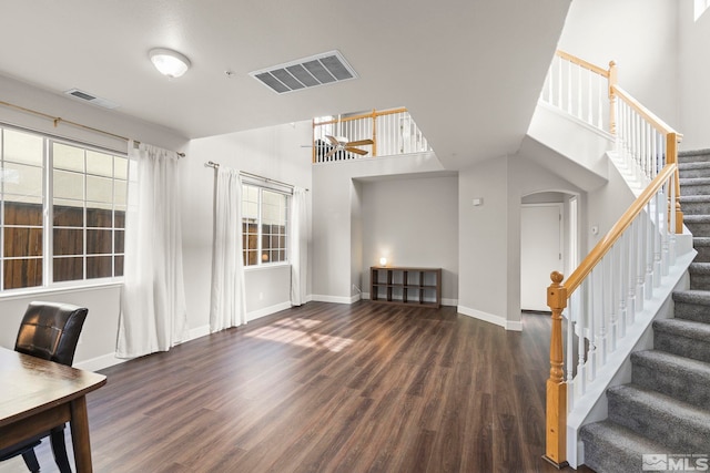 interior space with plenty of natural light, dark hardwood / wood-style flooring, and a high ceiling