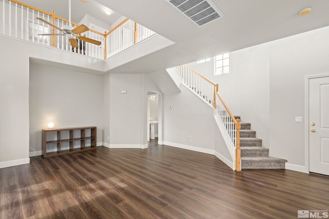 unfurnished living room featuring ceiling fan, a towering ceiling, and dark hardwood / wood-style flooring