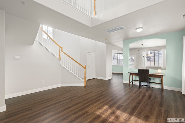 living room featuring a towering ceiling, dark hardwood / wood-style flooring, and a chandelier