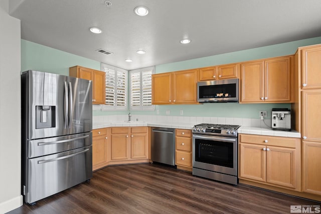 kitchen featuring dark hardwood / wood-style flooring, sink, tile countertops, and stainless steel appliances