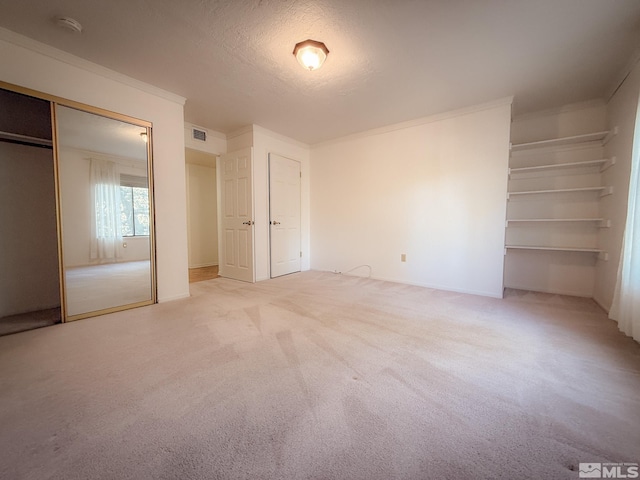 unfurnished bedroom featuring light carpet, ornamental molding, a closet, and a textured ceiling