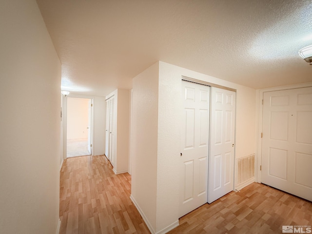 corridor featuring light hardwood / wood-style floors and a textured ceiling