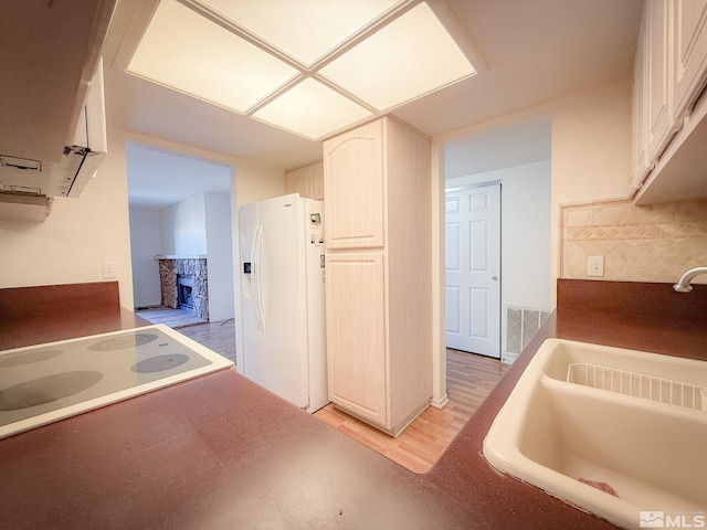 kitchen with white cabinets, white refrigerator with ice dispenser, sink, and light wood-type flooring