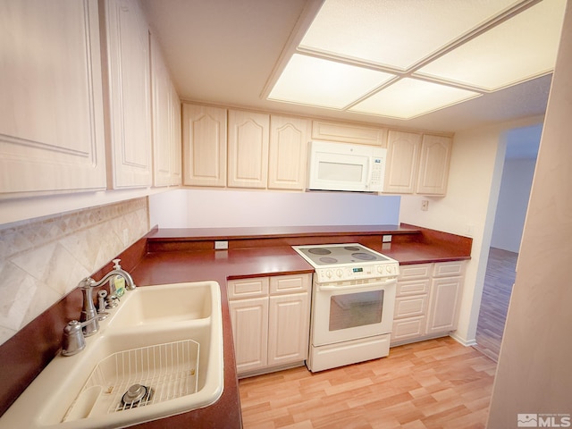 kitchen with sink, white appliances, and light hardwood / wood-style floors