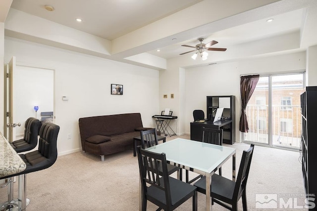 carpeted dining room featuring ceiling fan and a raised ceiling